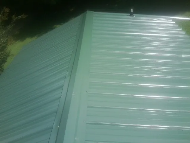 New green metal panels meeting at the ridge of a roof — Flat Roof Repair work by our crew in Warm Springs
