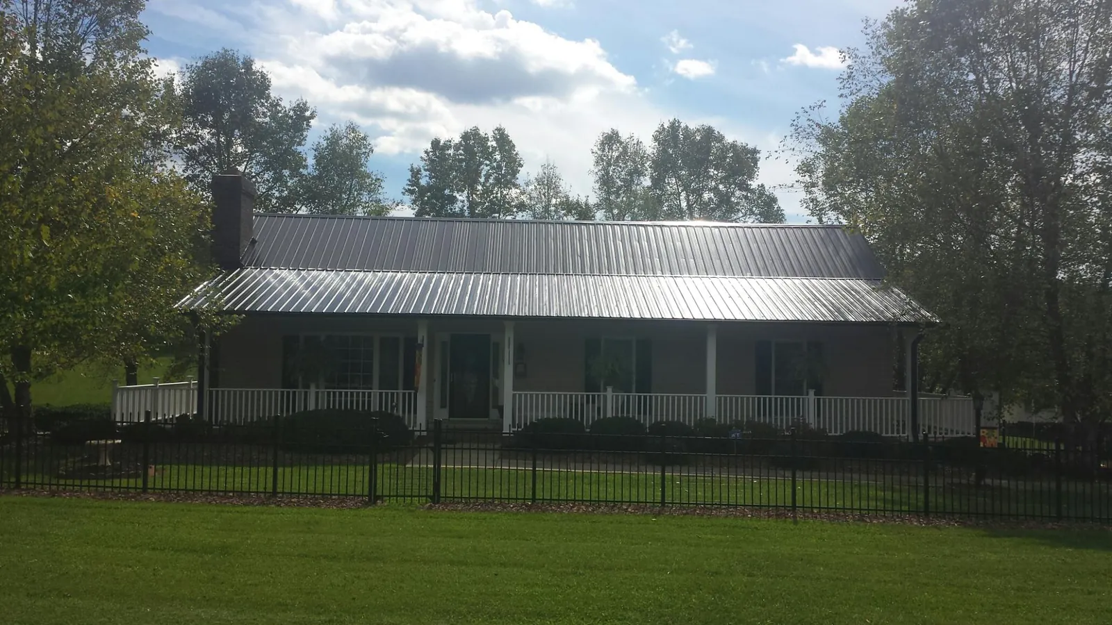 Gray metal roof on a brick ranch with a full width front porch — Gutter Guard Installation work by our crew in Warm Springs