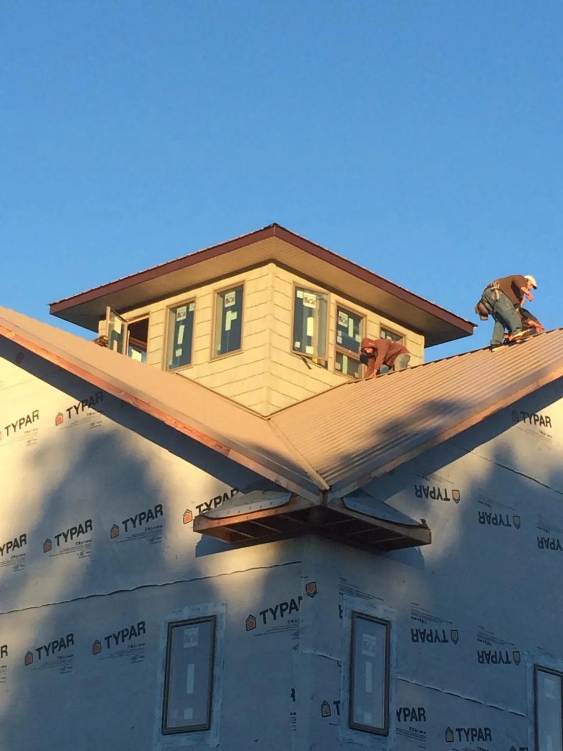 Roofers working around a rooftop cupola on a new metal roof at sunset — Roof Waterproofing in Warm Springs by Roofing Brothers